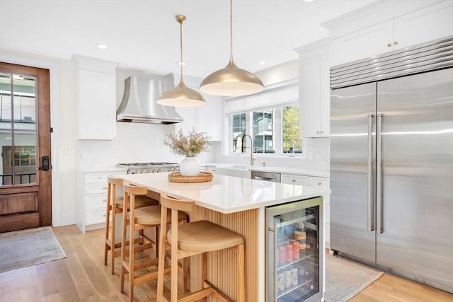 7 Newman St, Cambridge, MA 02140 - kitchen with stainless steel appliances, wine cooler, premium range hood, a sink, and light wood-style floors