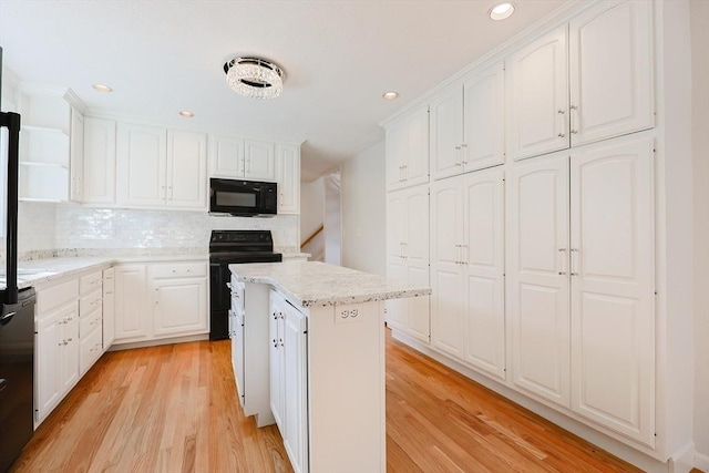 kitchen featuring white cabinetry, a center island, light wood-type flooring, and black appliances