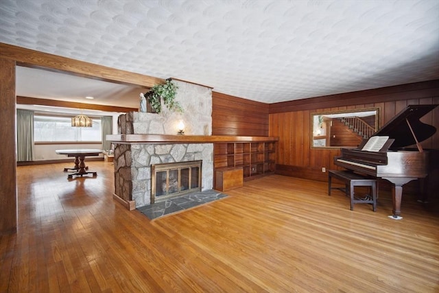 living room with hardwood / wood-style floors, a fireplace, beamed ceiling, and wood walls