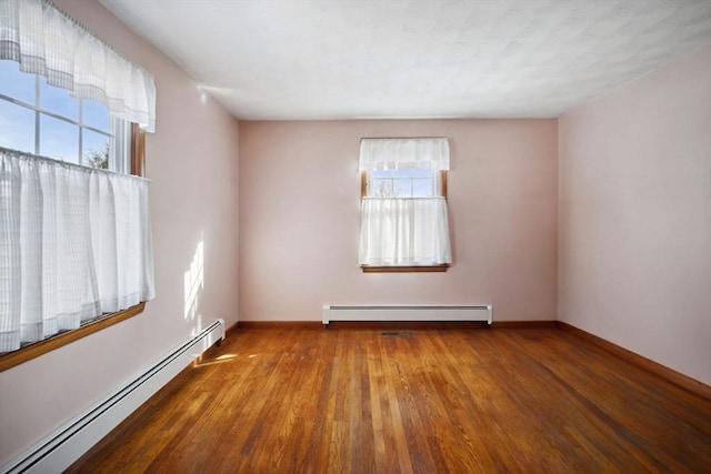 spare room featuring wood-type flooring and baseboard heating