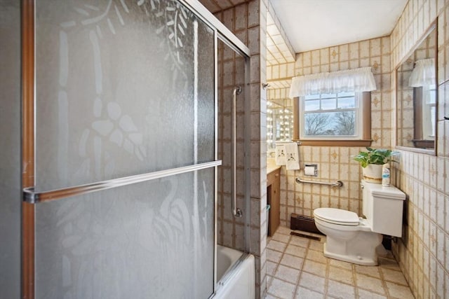 full bathroom with vanity, toilet, combined bath / shower with glass door, and tile walls