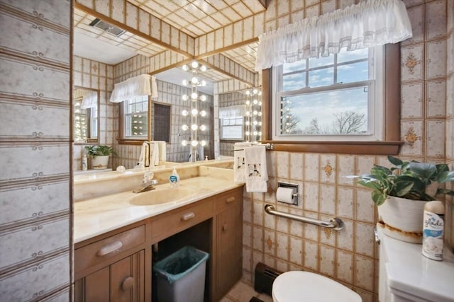 bathroom featuring vanity, tile walls, an inviting chandelier, and toilet