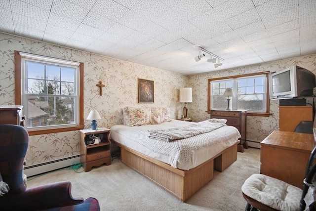 bedroom with multiple windows, a baseboard radiator, and light colored carpet