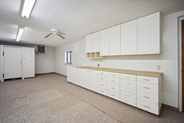 kitchen featuring ceiling fan, a textured ceiling, and white cabinets