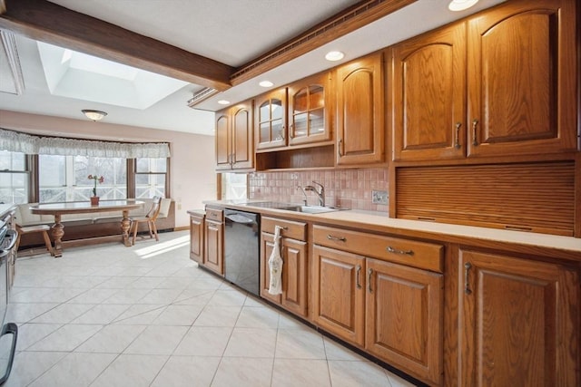 kitchen featuring light tile patterned flooring, sink, tasteful backsplash, a skylight, and dishwasher