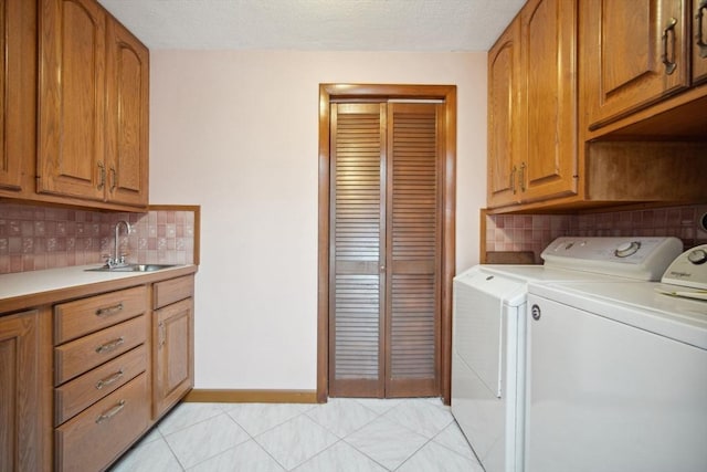 clothes washing area featuring cabinets, washing machine and clothes dryer, sink, and light tile patterned floors