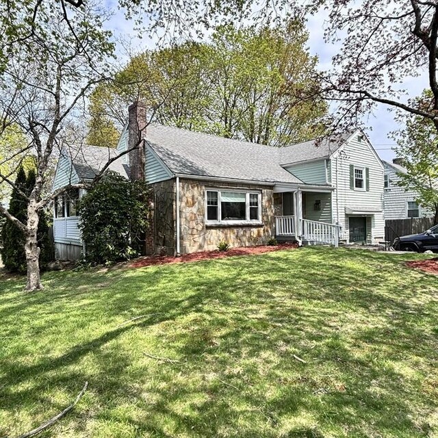 tri-level home featuring a chimney, a front yard, stone siding, and a porch