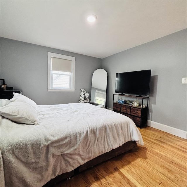 bedroom featuring arched walkways, baseboards, and light wood-style floors