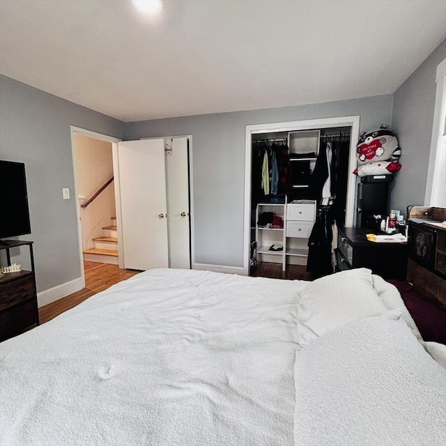 bedroom featuring two closets, baseboards, and wood finished floors