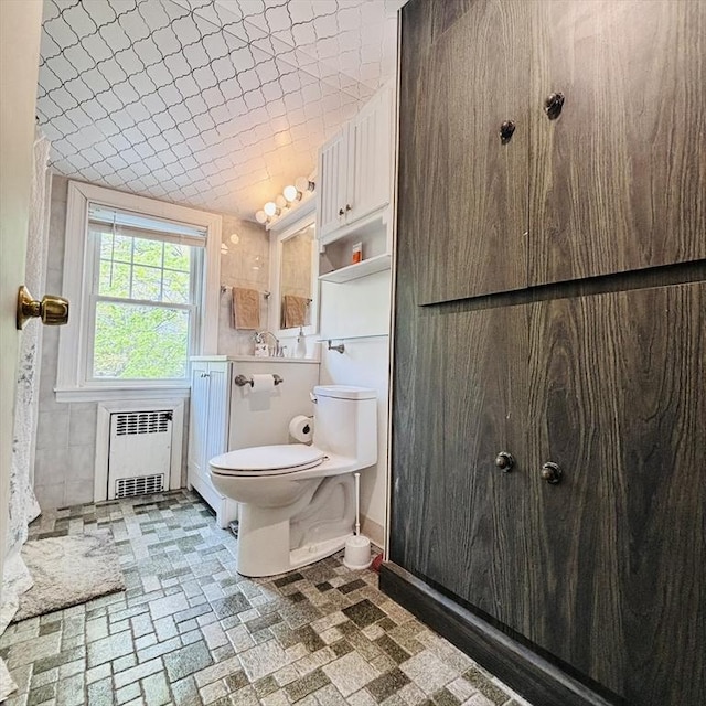 bathroom featuring baseboards, a sink, radiator, and toilet