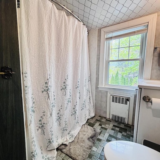full bath with radiator heating unit, toilet, and curtained shower