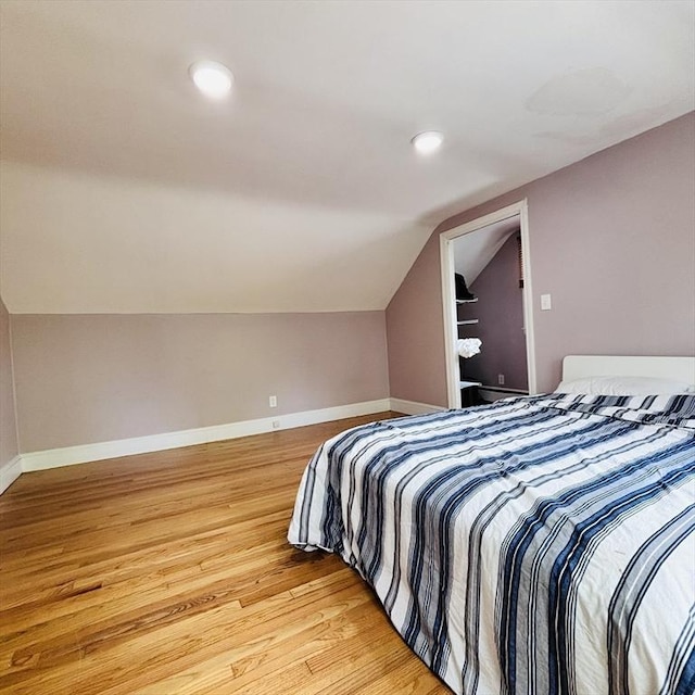 bedroom with baseboards, recessed lighting, light wood-style flooring, and lofted ceiling