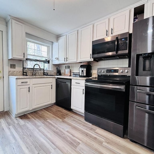 kitchen with a sink, appliances with stainless steel finishes, white cabinets, and tasteful backsplash
