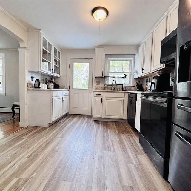kitchen with light wood-style floors, glass insert cabinets, white cabinets, and black appliances