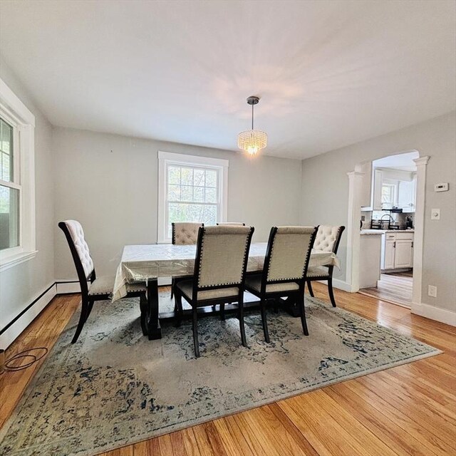 dining area with ornate columns, baseboards, and light wood-type flooring