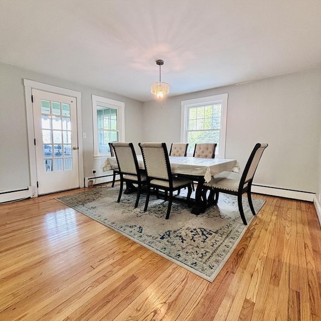 dining room with a healthy amount of sunlight, a baseboard heating unit, and wood finished floors