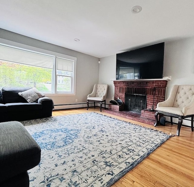 living room featuring recessed lighting, a baseboard heating unit, a brick fireplace, and wood finished floors
