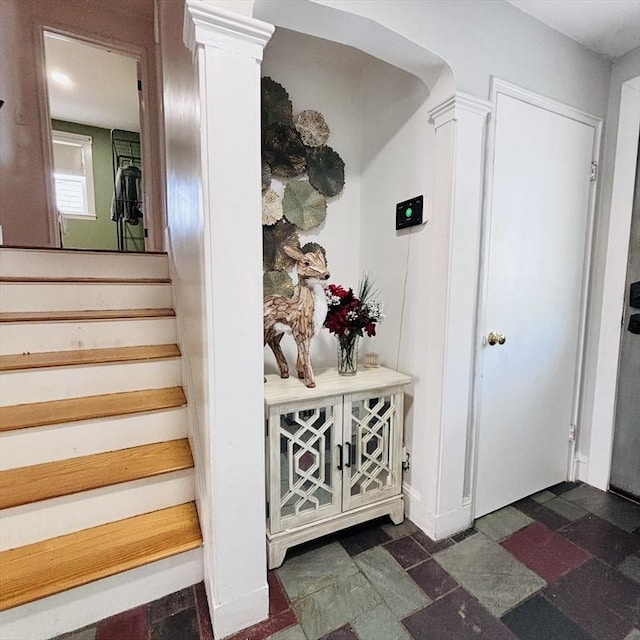 stairs featuring decorative columns and stone finish floor