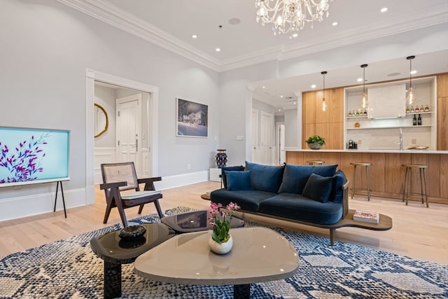 living room with crown molding, light hardwood / wood-style flooring, a chandelier, and sink