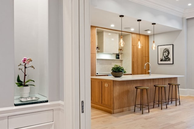 bar with pendant lighting, light wood-type flooring, and crown molding