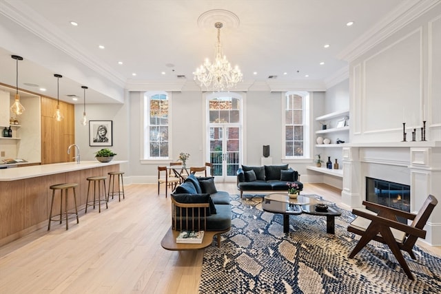 living room featuring french doors, sink, light hardwood / wood-style flooring, ornamental molding, and a notable chandelier