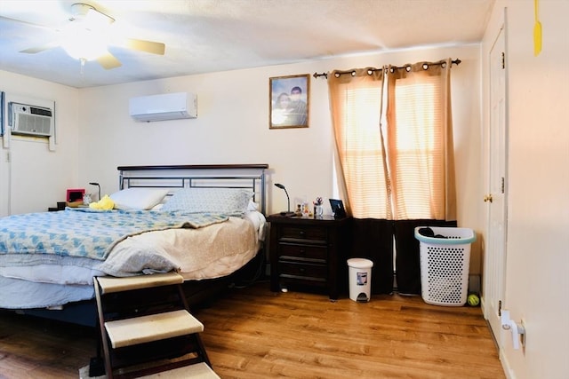 bedroom featuring a wall mounted AC and light hardwood / wood-style floors