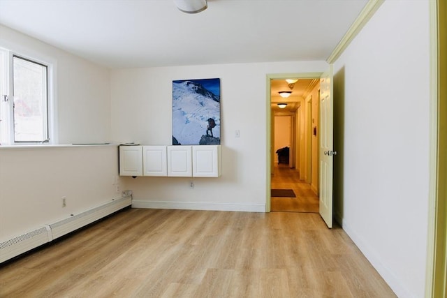 spare room with a baseboard heating unit and light wood-type flooring