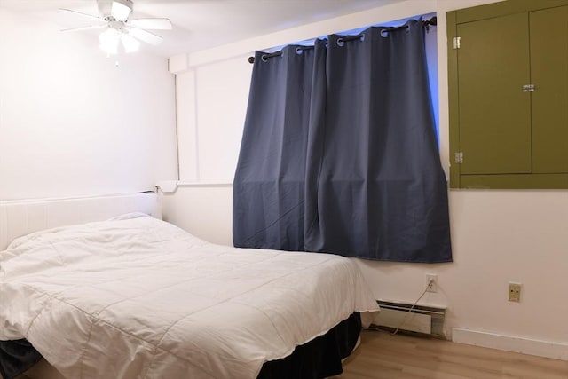 bedroom featuring wood-type flooring, ceiling fan, and baseboard heating