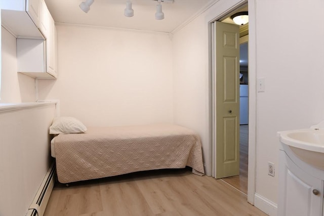 bedroom with crown molding, ceiling fan, light hardwood / wood-style floors, and baseboard heating