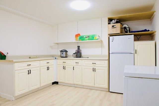 kitchen with white fridge, white cabinets, and light hardwood / wood-style flooring