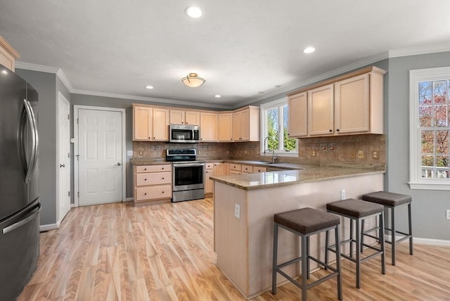 57 Bouffard Dr, Marlborough, MA 01752 - kitchen featuring light brown cabinets, light wood-style flooring, stainless steel appliances, a peninsula, and backsplash