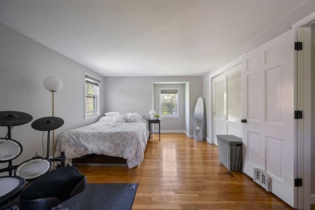 bedroom featuring baseboards, a closet, wood finished floors, and visible vents