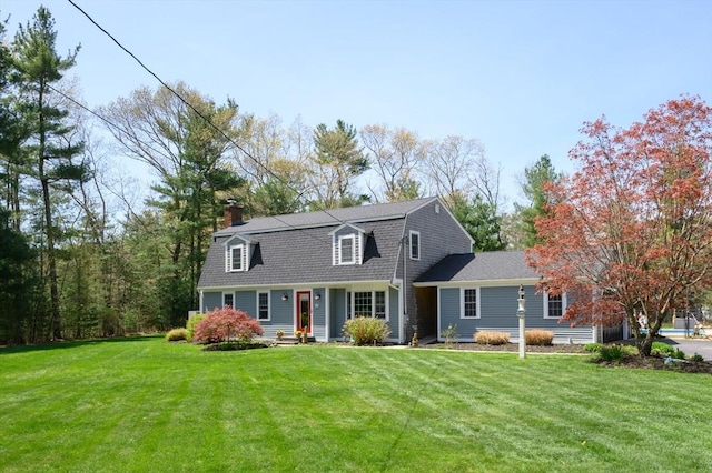 colonial inspired home with roof with shingles, a chimney, a front lawn, and a gambrel roof
