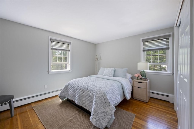 bedroom featuring baseboards, wood finished floors, and baseboard heating