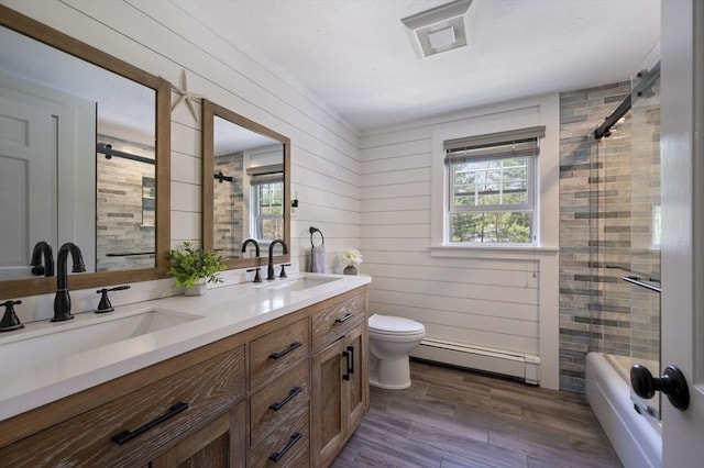 bathroom featuring a sink, a shower with door, a baseboard heating unit, and a wealth of natural light