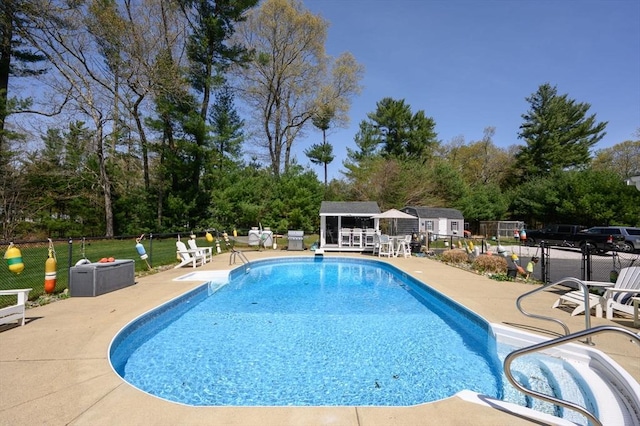 outdoor pool featuring fence, an outbuilding, and a patio area