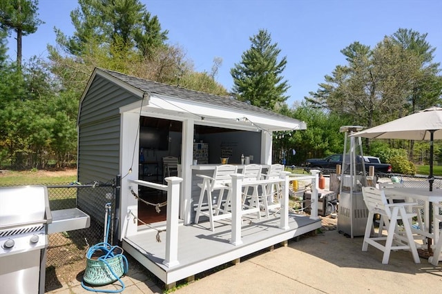view of outbuilding featuring fence, outdoor dining space, and an outbuilding