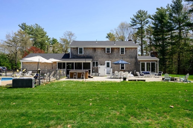 rear view of property with an outdoor pool, a chimney, a lawn, a patio, and a fire pit