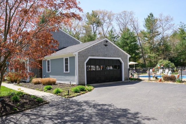 garage featuring fence, a fenced in pool, and aphalt driveway