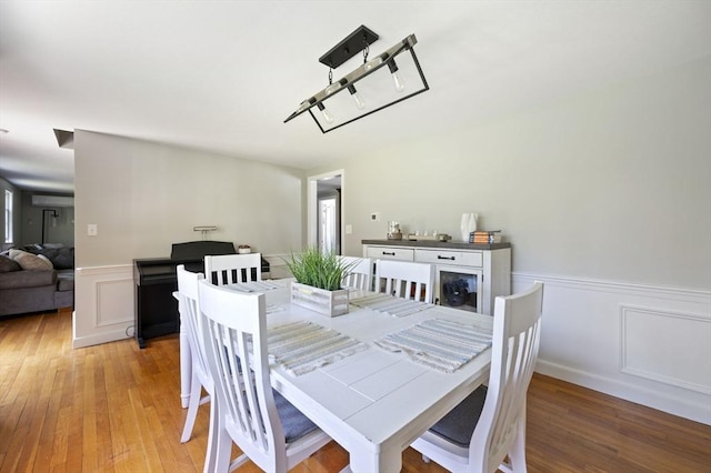 dining space featuring a decorative wall, light wood finished floors, and a wainscoted wall