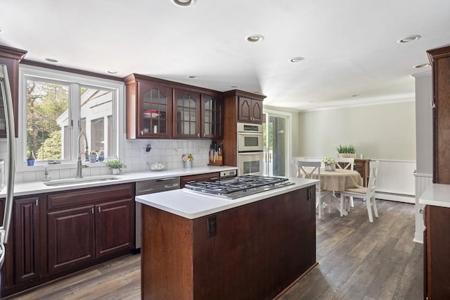 kitchen featuring light countertops, stainless steel appliances, a sink, and a wainscoted wall
