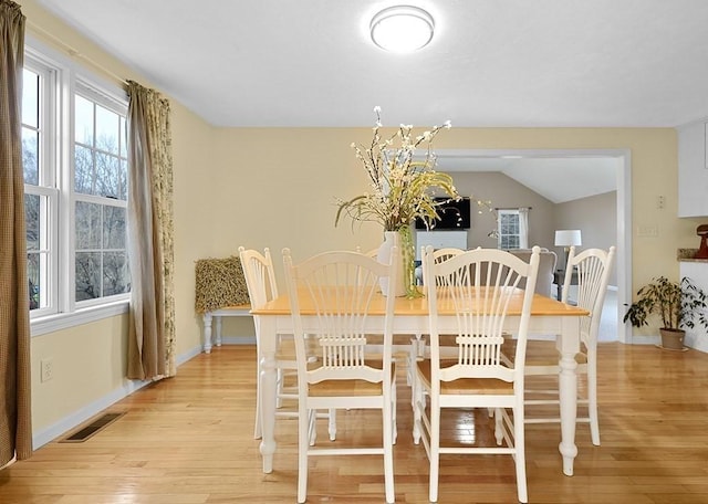 dining area featuring vaulted ceiling and light wood-type flooring