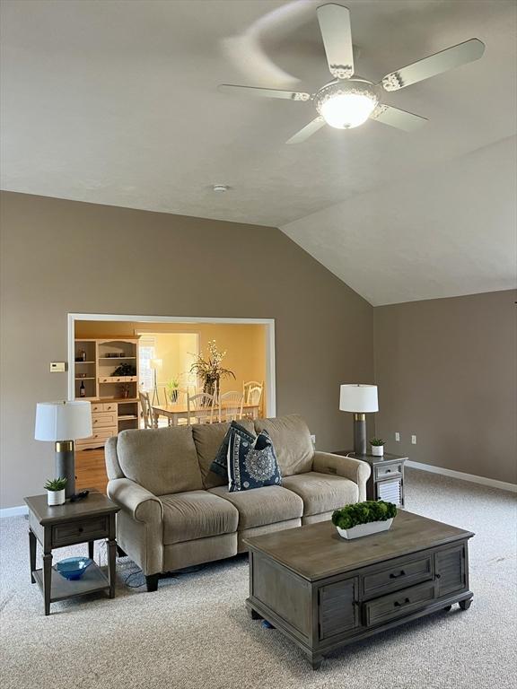 living room featuring light colored carpet, ceiling fan, and lofted ceiling