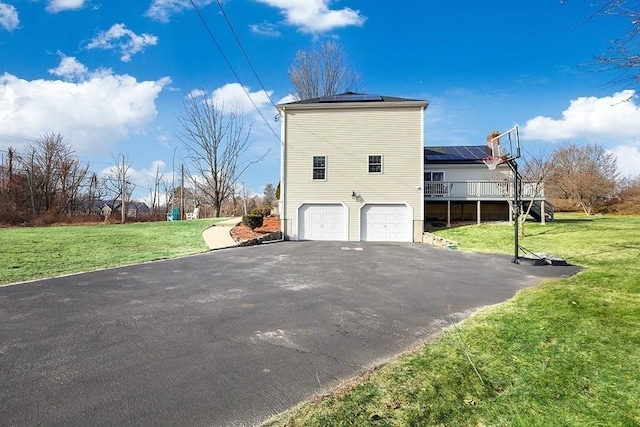 view of property exterior featuring solar panels, a garage, a wooden deck, and a lawn