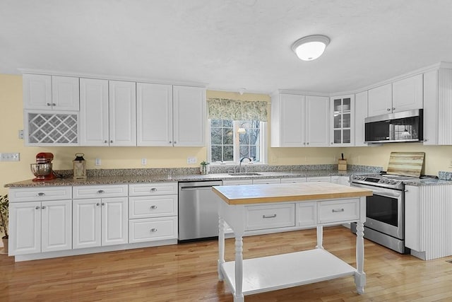 kitchen with sink, stainless steel appliances, wooden counters, light hardwood / wood-style floors, and white cabinets