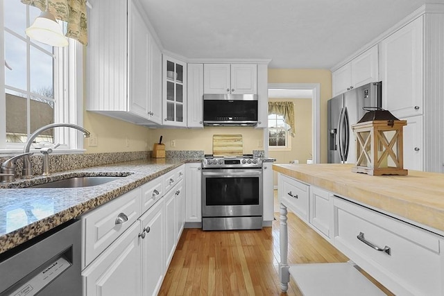 kitchen featuring white cabinets, light stone counters, sink, and appliances with stainless steel finishes