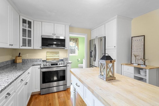 kitchen with light stone countertops, white cabinetry, appliances with stainless steel finishes, and light hardwood / wood-style flooring