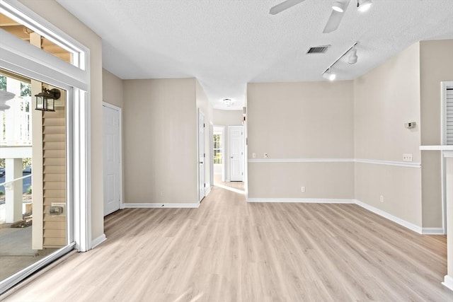 empty room featuring visible vents, light wood-style floors, plenty of natural light, and ceiling fan