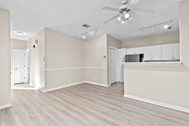 unfurnished living room with visible vents, a ceiling fan, light wood-type flooring, a textured ceiling, and rail lighting