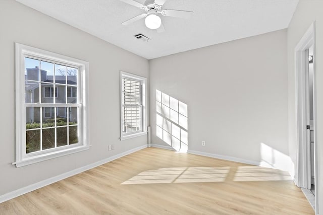 empty room featuring baseboards, visible vents, ceiling fan, and light wood-style floors